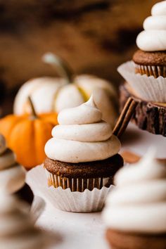 cupcakes with white frosting and pumpkins in the background