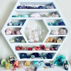 a white shelf filled with lots of different colored rocks and crystal quartzs on top of it