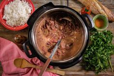 a pot filled with meat and rice next to other food on a wooden counter top