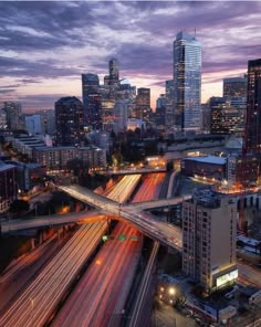 the city skyline is lit up at night with traffic moving on it's streets