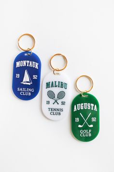 three different colored key chains with logos on them, one for the men's tennis team