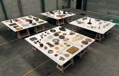 several tables with different items on them in a parking lot next to a storage building