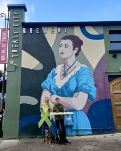 two people standing in front of a wall with a painting on it that says, elizabeth brewery