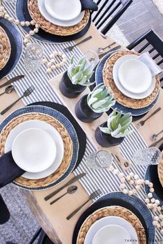 the table is set with black and white plates, silverware, and succulents