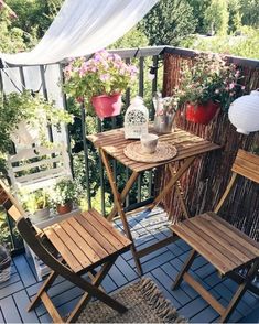 two wooden chairs sitting on top of a balcony next to plants and flowers in pots