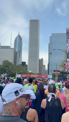 a large group of people walking down a street with tall buildings in the back ground