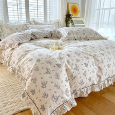 a bed with white sheets and pillows in a room next to a window filled with windows