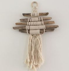 a piece of driftwood hanging on a wall with some tassels attached to it