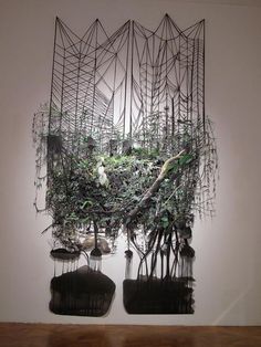 an art piece is hanging on the wall in front of two sculptures with plants growing out of them