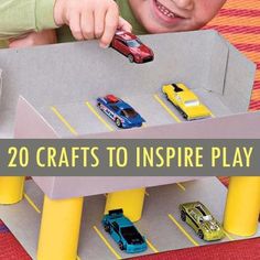 a young boy playing with toy cars in a play area that is made out of cardboard