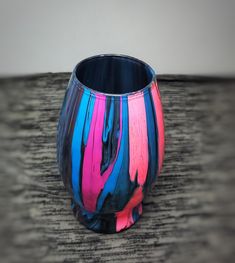 a multicolored vase sitting on top of a wooden table next to a wall