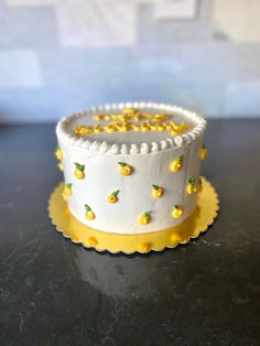 a white and yellow cake with pineapples on it sitting on a black table