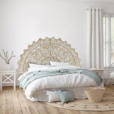 a bedroom with white walls and wood flooring has a large headboard on the bed