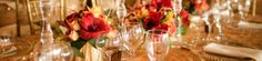 there are many wine glasses on the table with flowers in them and place settings for each one