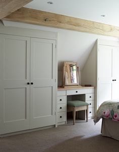 a bedroom with white cupboards and a small desk in the corner next to a bed