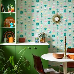 a dining room with green walls and colorful wallpaper on the walls, including a white table surrounded by chairs