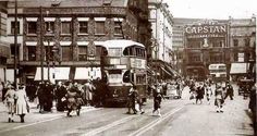 an old black and white photo of people walking down the street in front of double decker buses