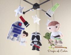 three felt mobiles hanging from the ceiling with star wars characters on them and one is holding a baby's toy