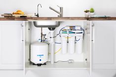 a kitchen sink under a counter with water tanks