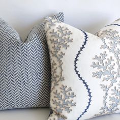 two blue and white pillows sitting on top of each other