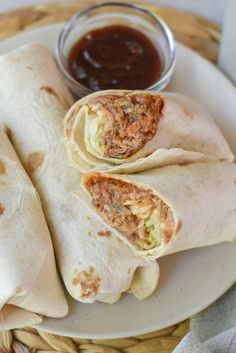 three burritos on a plate with dipping sauce