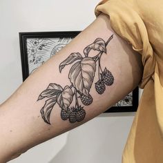 a woman with a tattoo on her arm has berries and leaves growing out of it