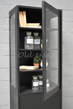 an open bookcase with books and jars on it in front of a brick wall