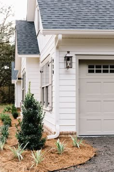 a white house with a black roof and two garage doors