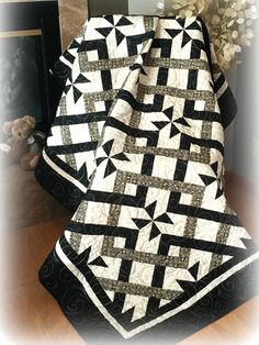 a black and white quilt sitting on top of a table next to a teddy bear