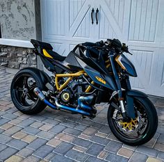 a black and yellow motorcycle parked in front of a garage