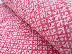 two pink and white pillows on top of each other in front of a bed sheet