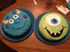 two cakes decorated to look like monsters sitting on top of a wooden table next to each other