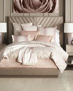 a bed with pink and white comforter in a bedroom next to a painting on the wall