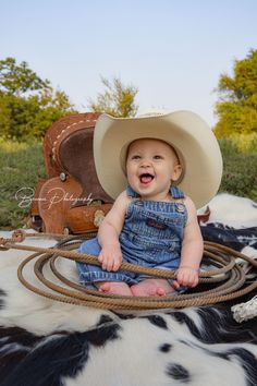 a baby sitting on top of a cow wearing a cowboy hat