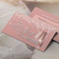 two pink business cards sitting on top of a marble table next to an envelope with the words refer a friend