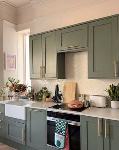 a kitchen with green cabinets and white counter tops