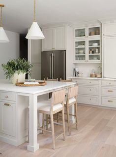 a kitchen with white cabinets and an island in the middle is surrounded by wooden flooring