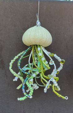 a green and white beaded jellyfish ornament hanging from a hook on a wall