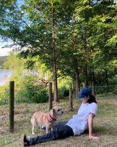 a person laying on the ground with a dog in front of them and some trees