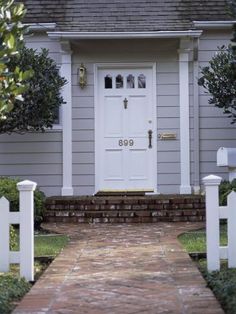 a white door and some bushes in front of a house