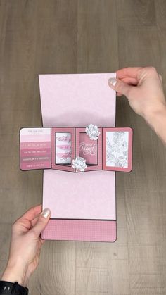 two hands holding an open pink folder with cards inside it on top of a wooden table