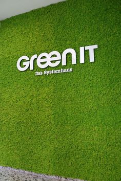 the green it logo is displayed on an artificial grass wall