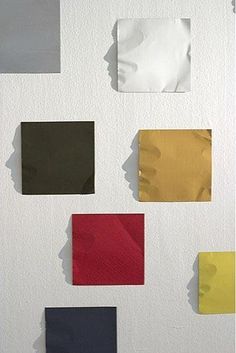 several different colors of paper on a white wall