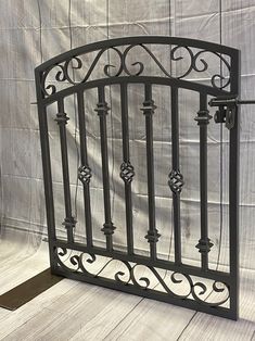 an iron gate is shown against a white wall with wood flooring and fabric behind it