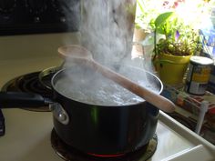 steaming water in a pot on the stove with a wooden stick sticking out of it