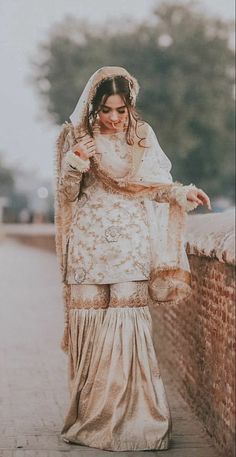 a woman in a wedding dress leaning against a wall