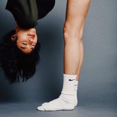 a woman doing a handstand on her head while wearing white socks and black shorts