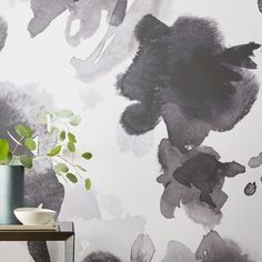 a vase sitting on top of a table next to a wall with black and white paint