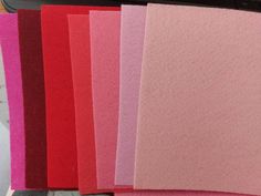 there are many different colors of paper on the table next to each other, including pink and red