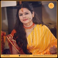 a woman in yellow and red sari with gold jewelry on her face, posing for the camera